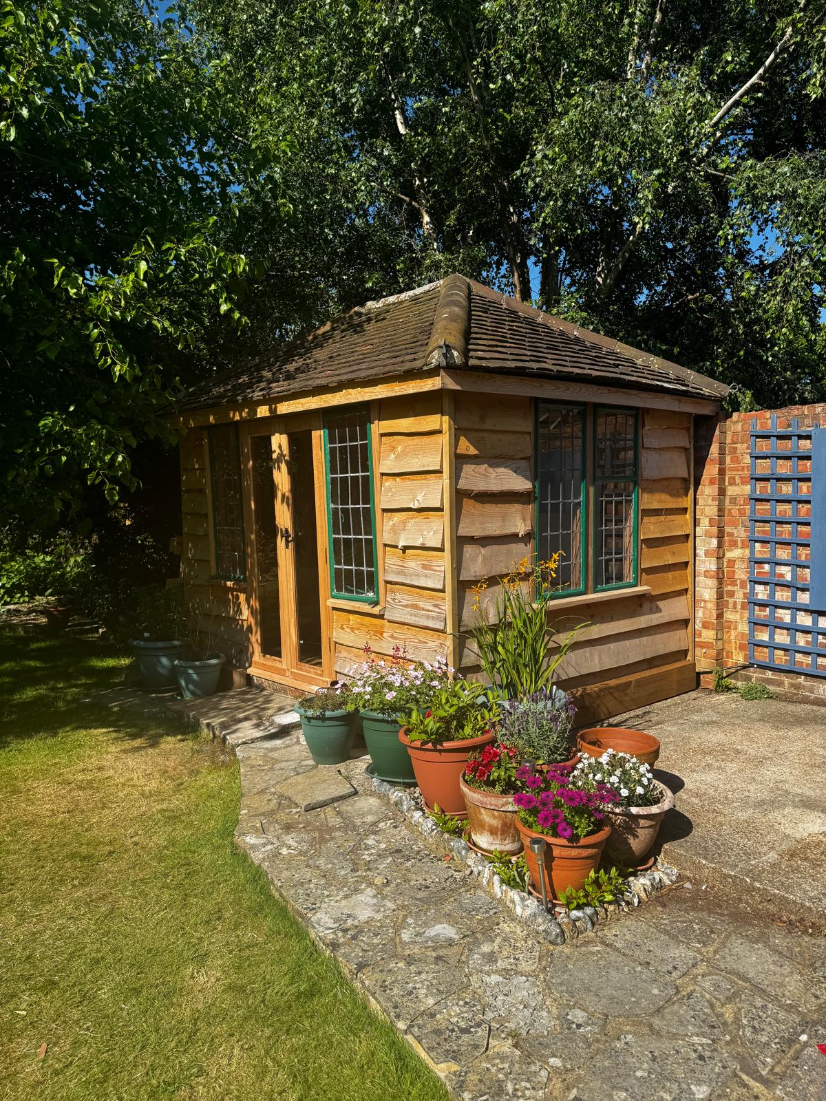  Wooden overlapping cladding on the exterior of a summer house with green window frames 