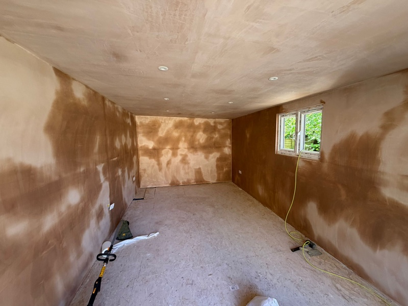  The interior of a garden room with freshly plastered walls and ceiling, featuring recessed spotlighting and a small side window 