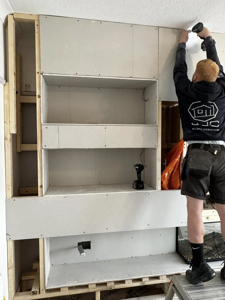 A JJC carpenter boarding out a media wall